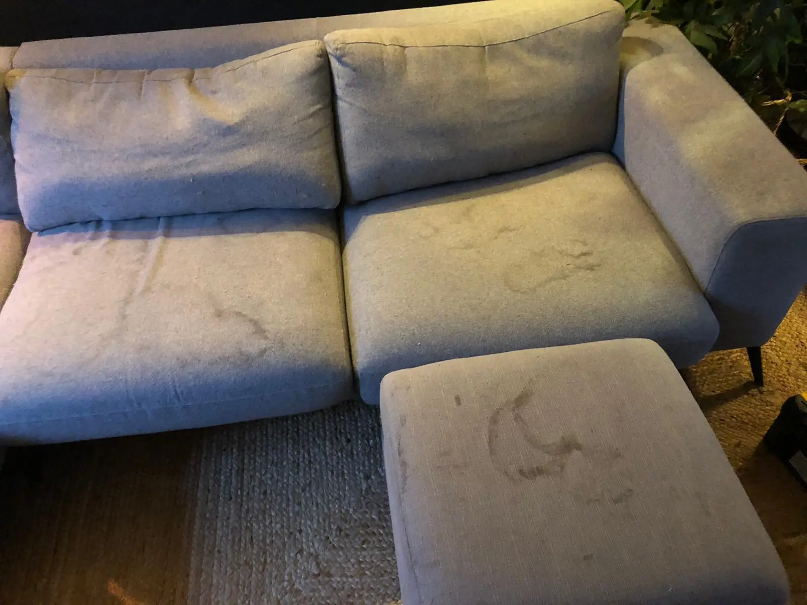 Grey sofa with visible stains before upholstery cleaning